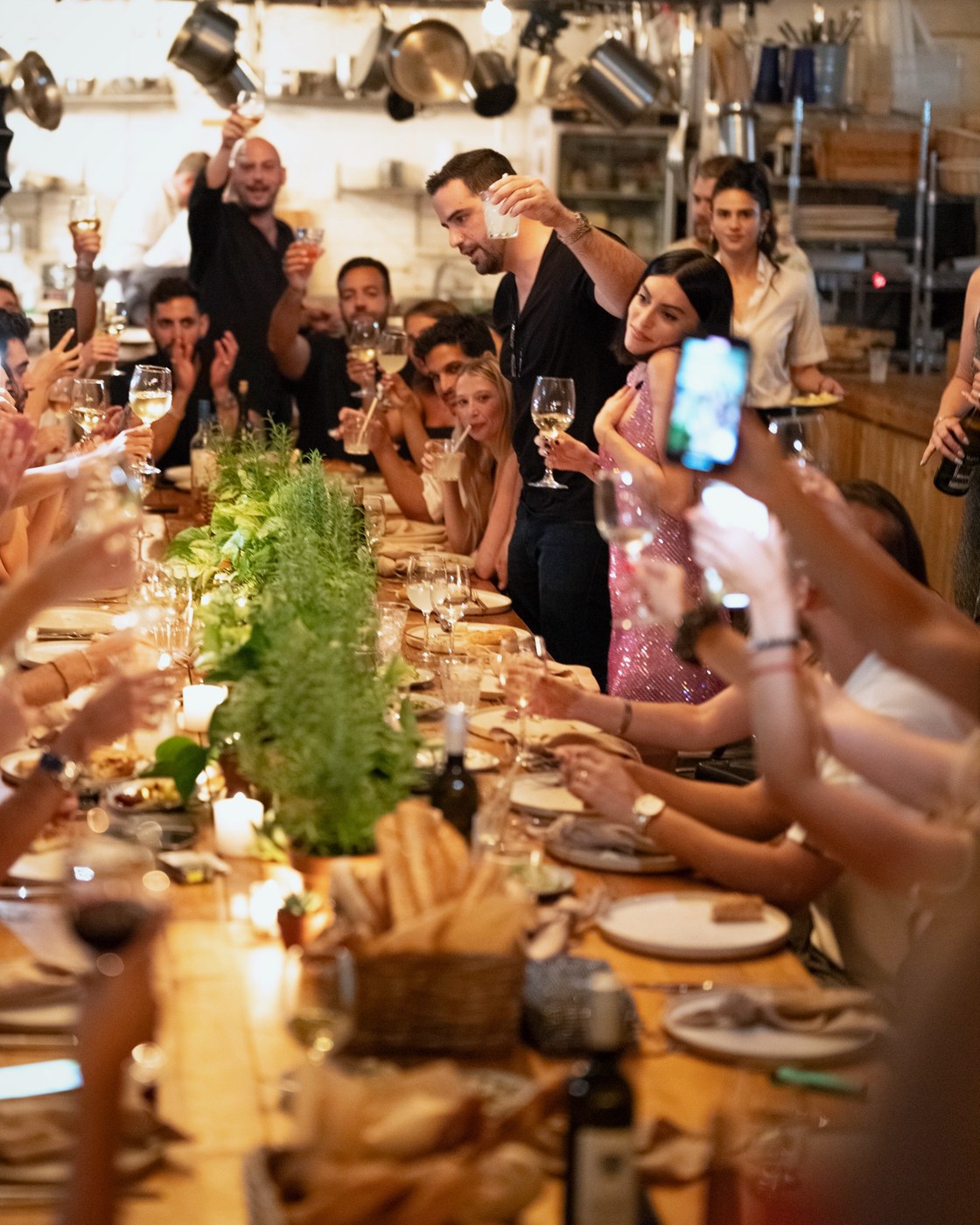 Guests raising their glasses around a long candlelit table